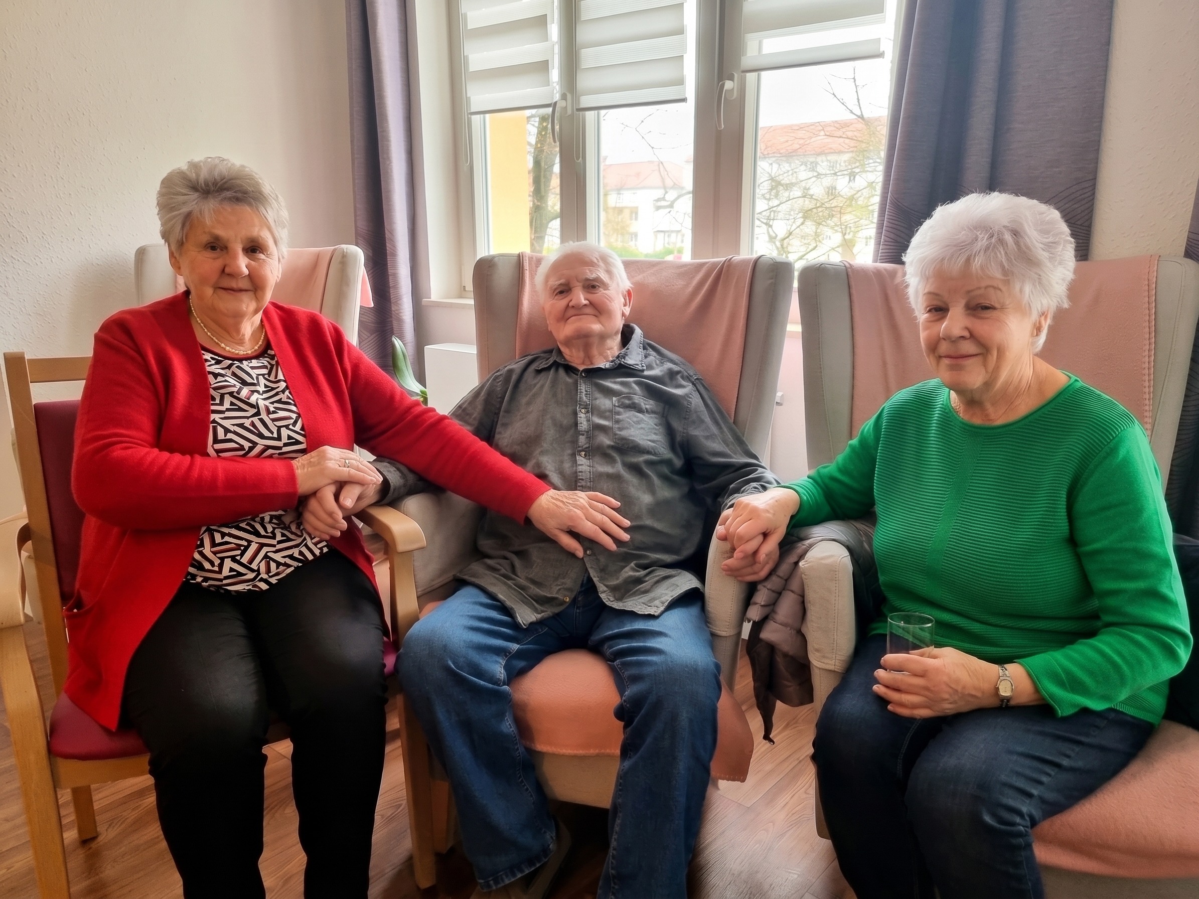 Drei Senioren sitzen beieinander und halten sich vertraut an den Händen, ein Symbol für die emotionale Begleitung der Gute Seele Alltagsbetreuung Wittenberg.