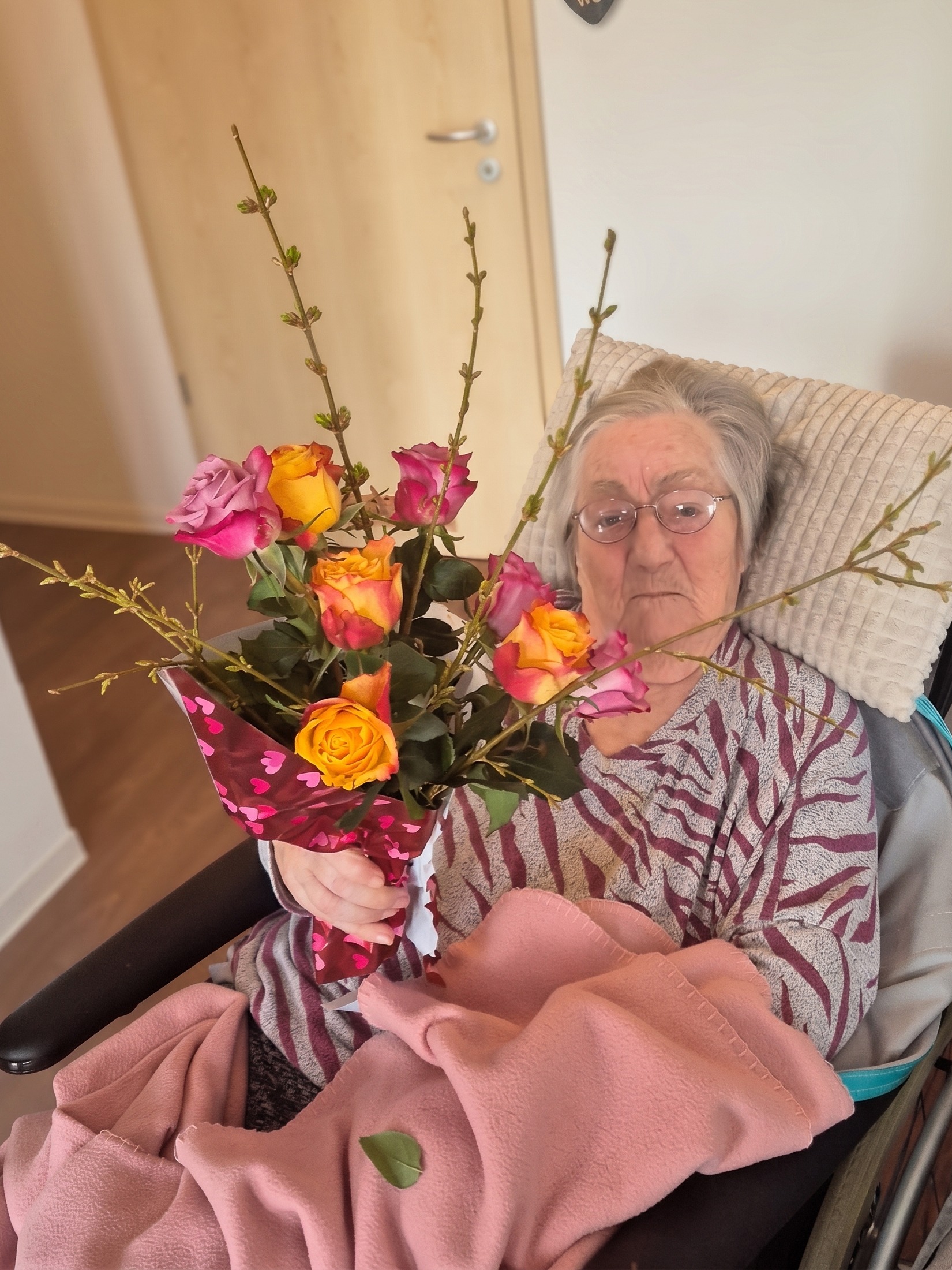 Ältere Frau freut sich über einen wunderschönen Rosenstrauß, ein Moment der Wertschätzung durch die Gute Seele Alltagsbetreuung Wittenberg.